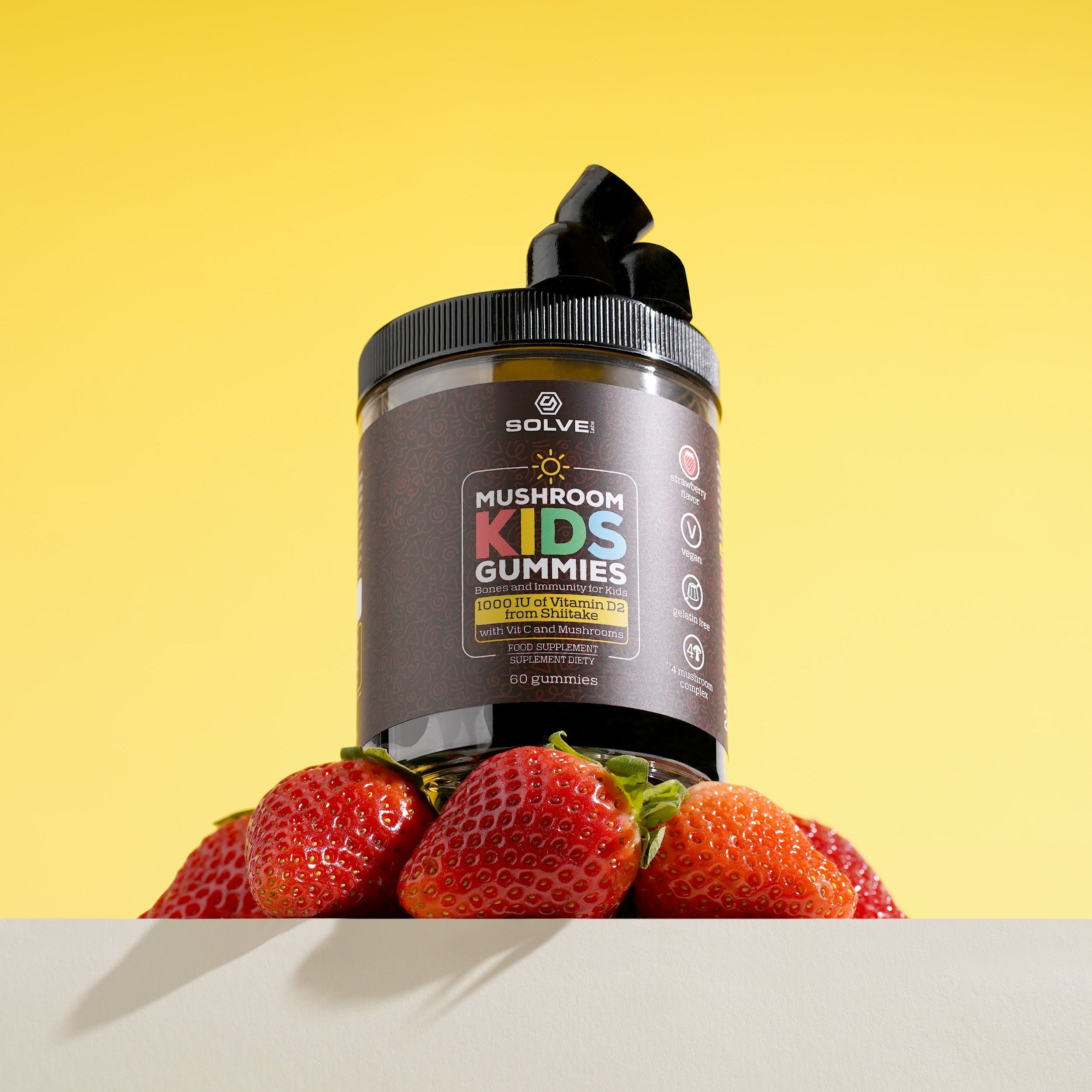 Container of 'Solve' Mushroom Kids Gummies with strawberries on a yellow background
